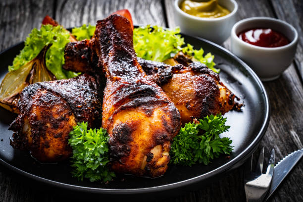 Roast chicken drumsticks and vegetables served on wooden table
